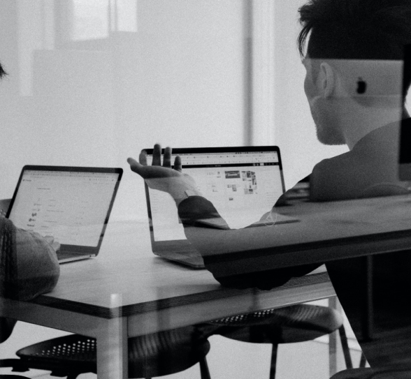 A man sat at a desk with hand out and palm up next to a colege
